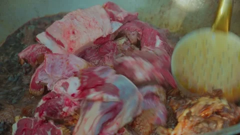 Chef Stirring Meat and Onions in Hot Oil in Large Kazan for Uzbek Plov, Close-Up Stock Footage 346702817