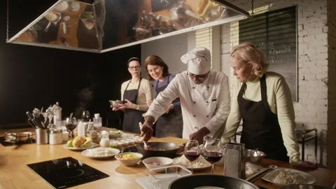 Chef Stirring Meat in Pan While Group of Excited Women Observing at Master Class Stock Footage 332572612