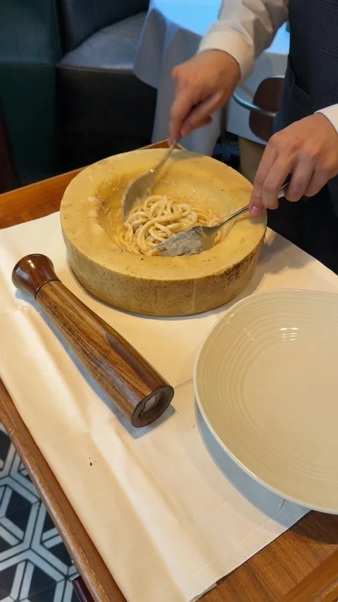 Chef stirring pasta inside a giant cheese wheel Stock Footage 340581415