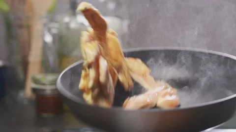 Chef stirring pieces chicken breasts in frying pan, slow motion. Stock Footage 154369965