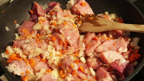 Chef stirring pork and vegetables in a pan Vidéo 342758734