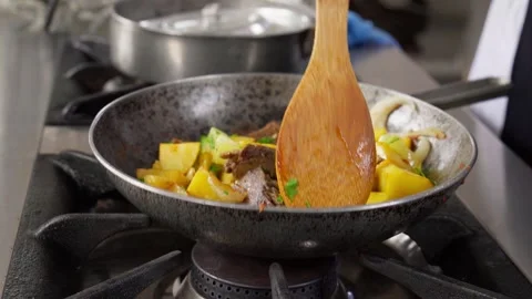 Chef stirring potatoes and meat in frying pan Stock Footage 286309928