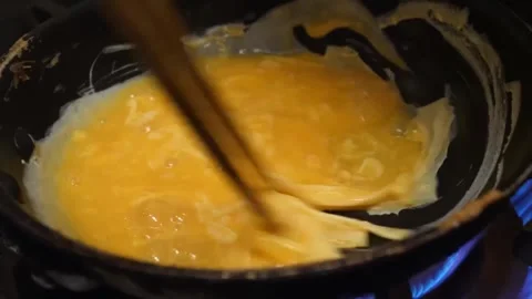 Chef Stirring Raw Beaten Eggs with Chopsticks in Pan on Gas Stove 스톡 동영상 347688228