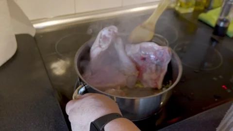 Chef stirring raw chicken pieces in a steaming pot Stock Footage 334177698