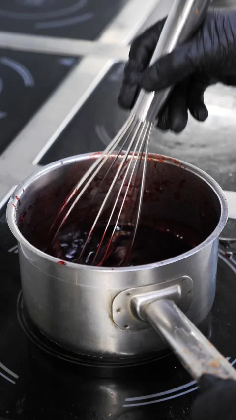 Chef stirring red berry sauce with a whisk in a saucepan on stove. Stock Footage 341286167