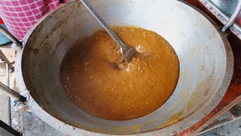 Chef stirring a rich meat broth simmering in a large pot. Stock Footage 324572942