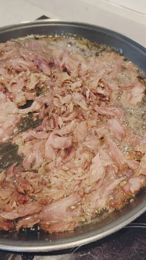 Chef stirring shredded duck confit with a wooden spoon in a hot frying pan with Stock Footage 344401861