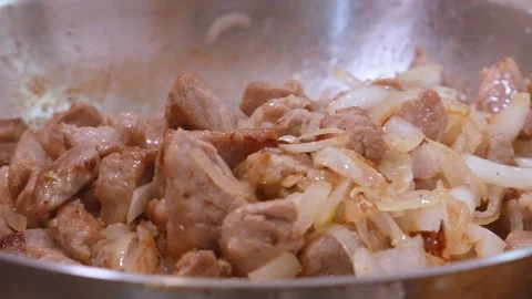 Chef stirring sizzling pork and onions in pan Видео 334758534