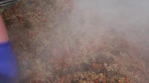 Chef stirring a steaming traditional pilaf dish with rice, meat, and vegeta.. Stock Footage 318004583