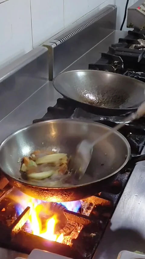 Chef stirring vegetables in wok pan on high gas stove flame. Stock Footage 340011652
