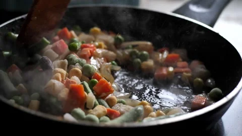Chef stirs assorted frozen vegetables in a frying pan. mixed colorful vegetables Stock Footage 263491223