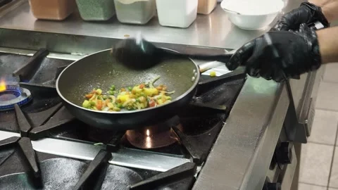 Chef stirs basmati rice with vegetables and spices in a frying pan over a Stock Footage 345364016
