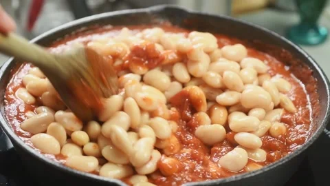 The chef stirs the boiled white beans and the sauce into the pan. Stock Footage 202177019