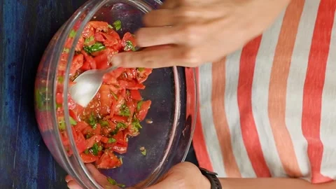 The chef stirs chopped tomatoes and basil in the glass bowl. Vertical video. Video stock 333708383