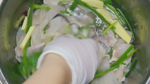 The chef stirs the fish fillets with ginger, scallions, and wine Stock Footage 319380572