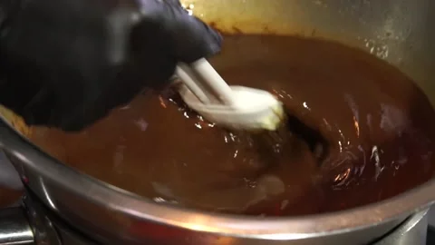 Chef stirs melted chocolate into containers Stock Footage 148315552
