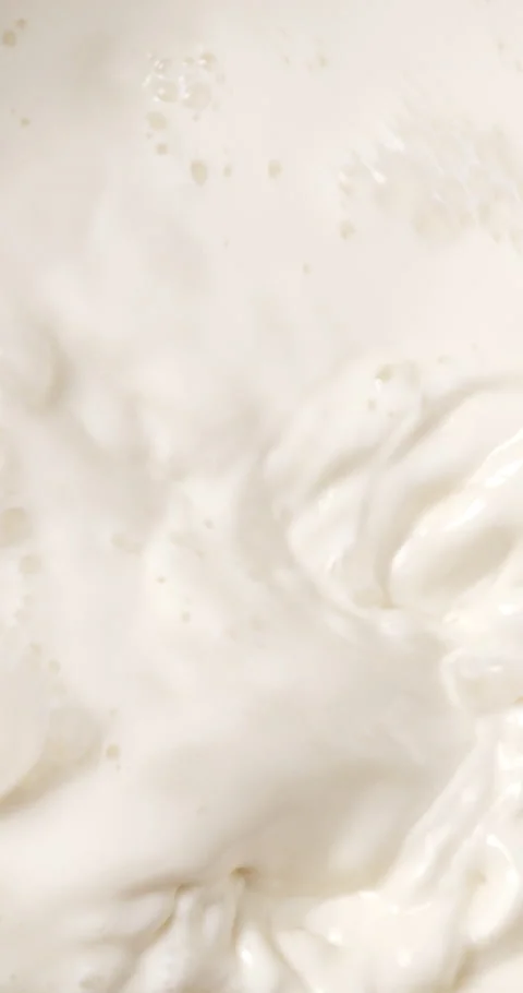 The chef stirs the milk with a spoon until it foams. Stock Footage 235899983
