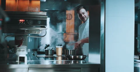Chef stirs pot while talking to person in kitchen Video stock 204973951