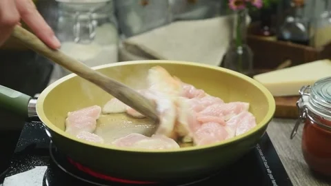 The chef stirs the raw chicken breast in the frying pan. Stock Footage 202072263