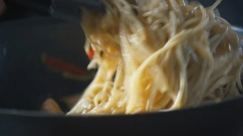 Chef stirs ready-made spaghetti pasta in a pan in a restaurant kitchen. Vidéo 124710851