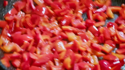 A chef stirs red bell peppers while they are frying in a pan. Slow motion 100fps Stock Footage 309299897