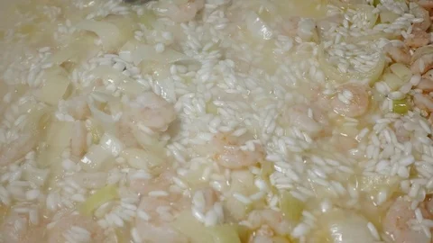 Chef stirs tasty risotto rice with prawns frying on white ceramic pan . Closeup Stock Footage 86972562