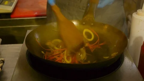 The chef stirs vegetables in a frying pan wok with a wooden spatula Stock Footage 84252209