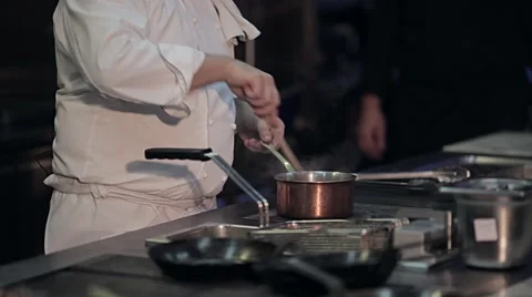 Chef at the stove with a spoon stirs Stock Footage 63825709