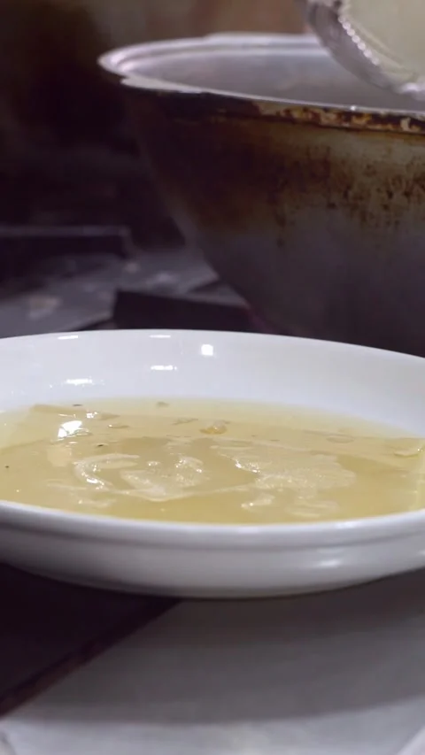 Chef straining boiled dough sheets for beshbarmak using a wire skimmer into a wh Stock Footage 342627959