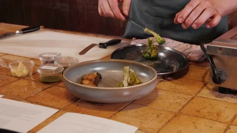 The chef on the stream prepares a dish of fried fish with broccoli and sauce 動画素材 169313317