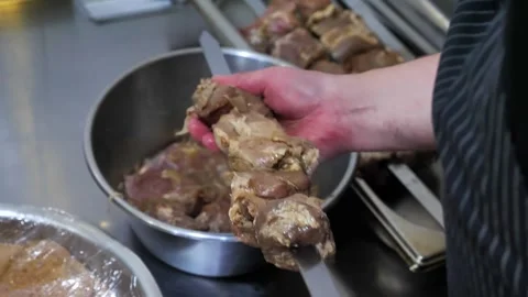 Chef stringing marinated raw meat pieces onto a metal skewer. Stock Footage 342255357