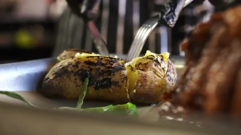 Chef in striped apron, black gloves cuts large baked potato with a cheese knife Stock Footage 141171130