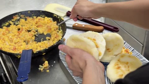 Chef stuffing arepas with scrambled eggs in a kitchen 스톡 동영상 344100206