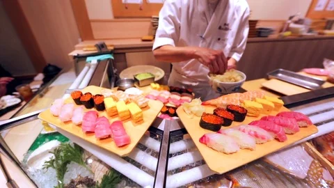 Chef in sushi restaurant prepares food in front of customers. Tokyo, Japan Stock Footage