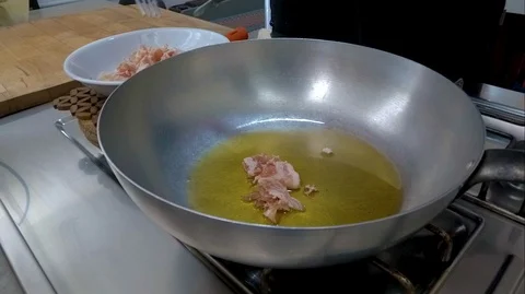 The chef takes the bacon from a white plate and puts it in the pan Stock Footage 101154985