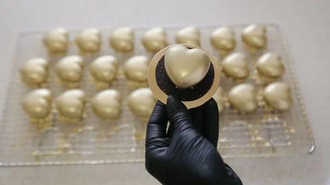 Chef takes one of lots heart shaped cakes with gold color edible coating Stock Footage 134681368
