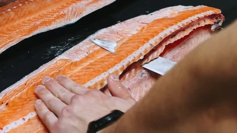 Chef takes out bones from the salmon fillet, cutting fish on slices for cooking Stock Footage 99228181