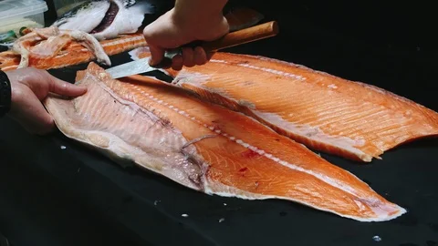 Chef takes out bones from the salmon fillet, cutting fish on slices for cooking Stock Footage 99229050