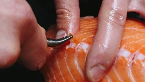 Chef takes out bones from the salmon fillet, cutting fish on slices for cooking Stock Footage 99229915