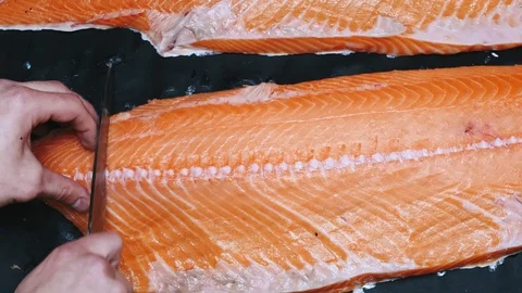 Chef takes out bones from the salmon fillet, cutting fish on slices for cooking Stock Footage 99230952
