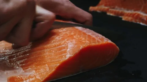 Chef takes out bones from the salmon fillet, cutting fish on slices for cooking Stock Footage 99231829
