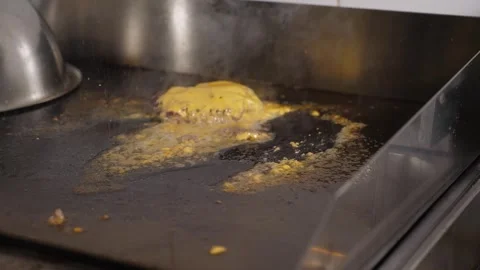 A chef takes out a cooked patty with melted cheese for a burger from a hot stove Stock Footage 288333928