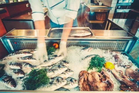 The chef is taking fresh fish from the counter. Fotos Stock