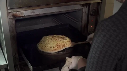 Chef taking out hot khachapuri out of the oven Stock Footage 73623142