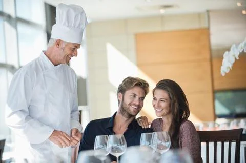 Chef talking to couple at restaurant Stock Photos