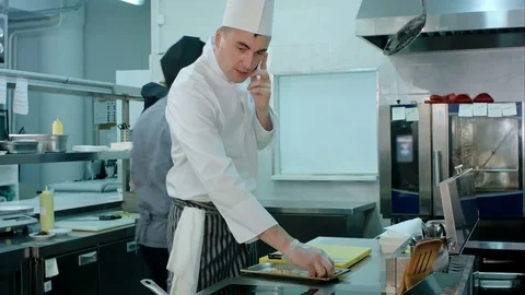 Chef talking on the phone and tossing ingredients on a frying pan in the 스톡 동영상 72327063