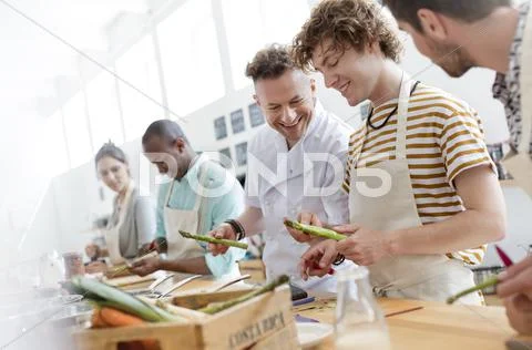 Chef teacher and students in cooking class kitchen Stock Photos