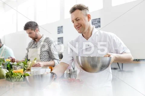 Chef teacher holding bowls in cooking class kitchen Stock Photos