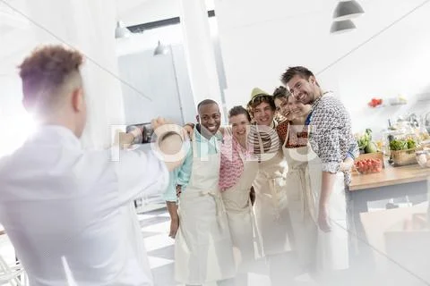 Chef teacher photographing students with camera phone in cooking class kitchen Stock Photos
