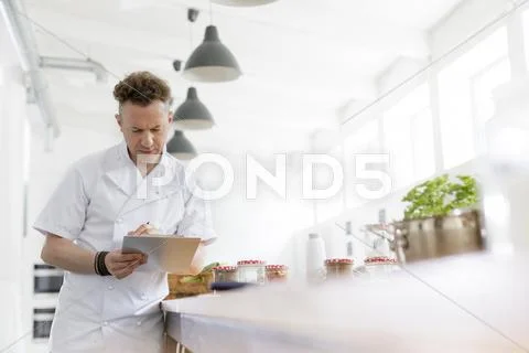 Chef teacher preparing with clipboard in cooking class kitchen Stock Photos